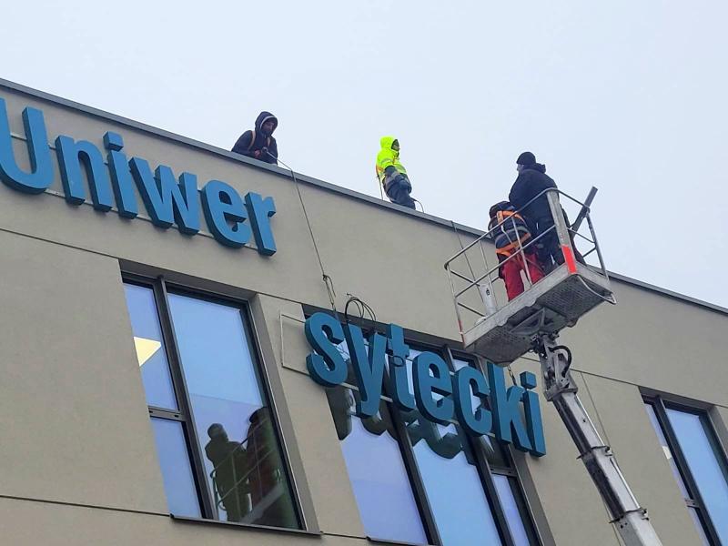 nowy szyld USK Nr 1 - zawieszanie na budynku 21.11.2023 (fot. Anna Guzowska)
